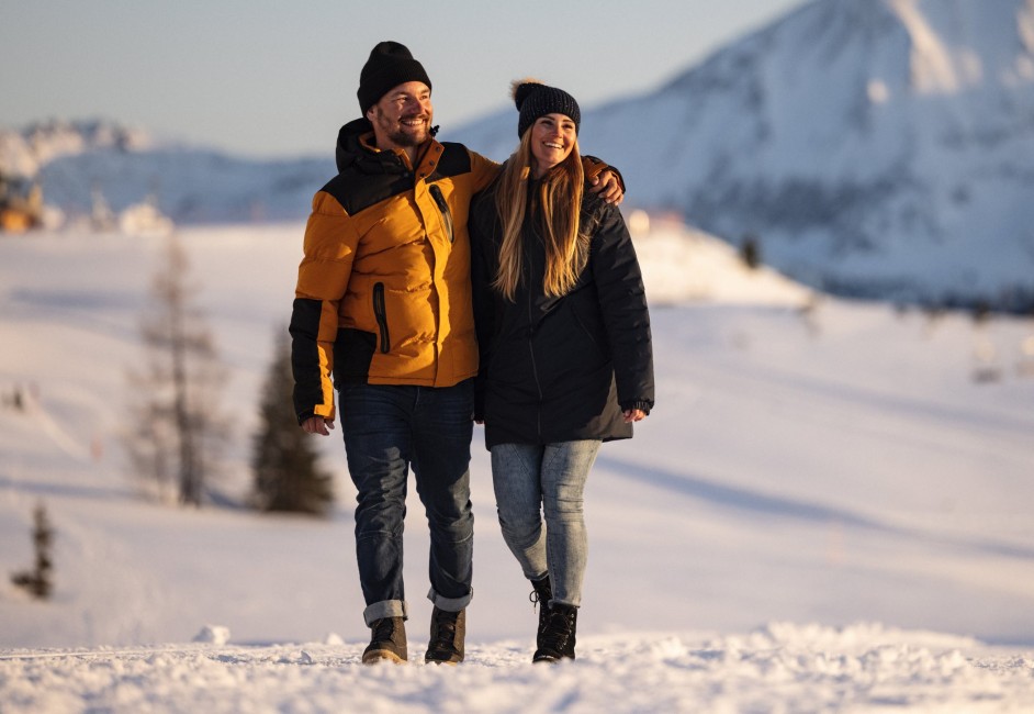 Ein Paar spaziert lächelnd im Schnee in Obertauern ©TVB_Obertauern