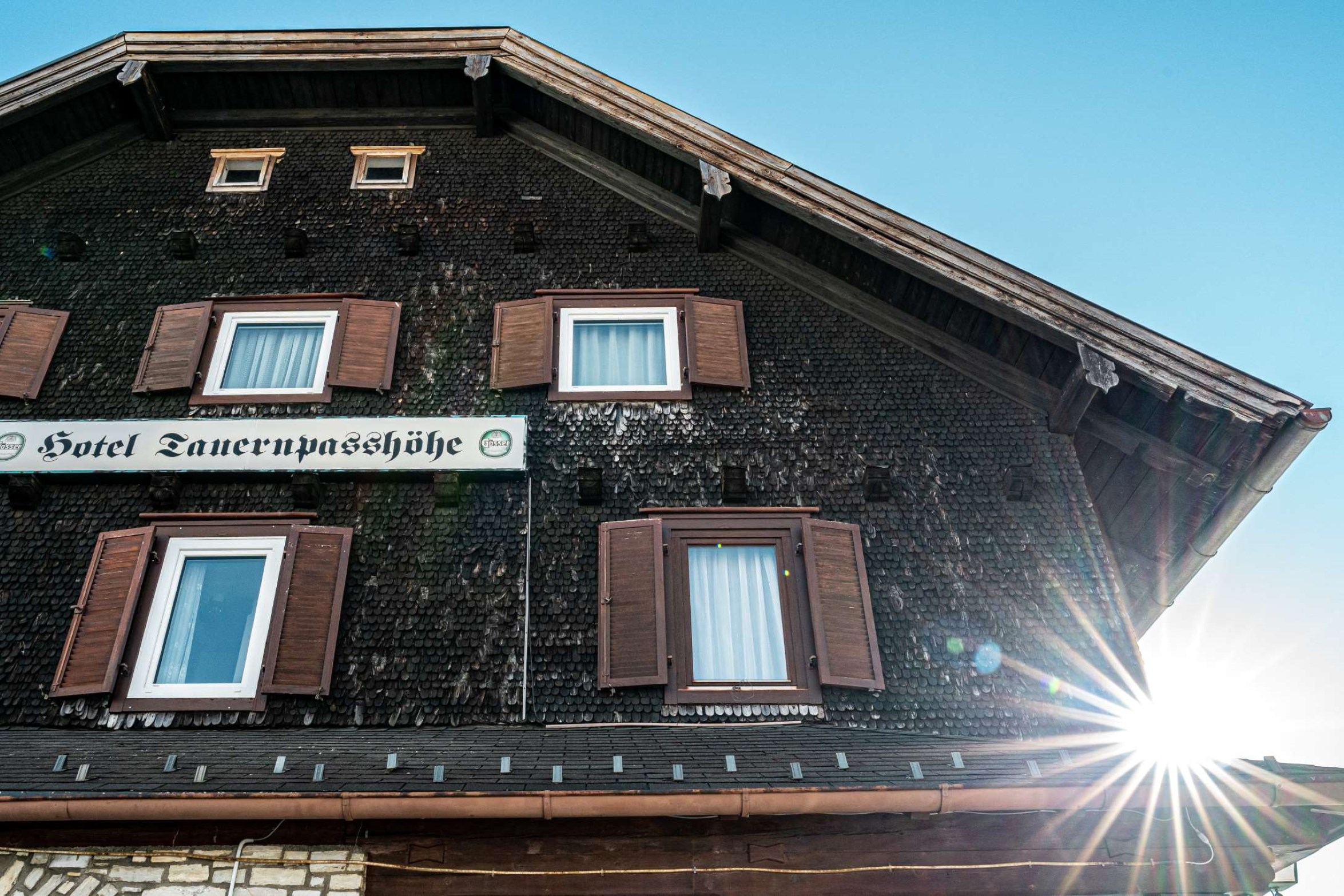 Fassade des Hotel Tauerpasshöhe in Obertauern mit Sonneschein, traditionelles Alpenhotel direkt an der Passhöhe.