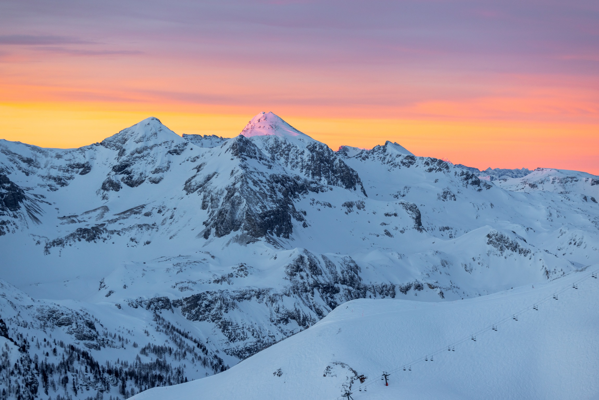Schneebedeckte Berge im Sonnenuntergang mit leuchtend orangefarbenem Himmel. ©TVB_Obertauern