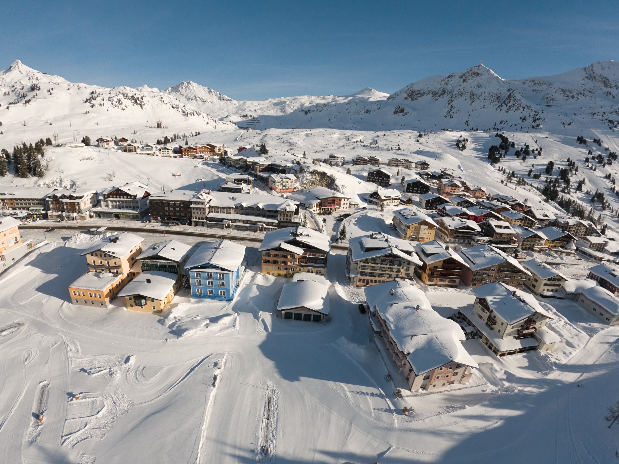 Winterliches Panorama von Obertauern mit zentraler Top-Lage der Wagner Hotels zwischen Skipisten und schneebedeckten Alpen.