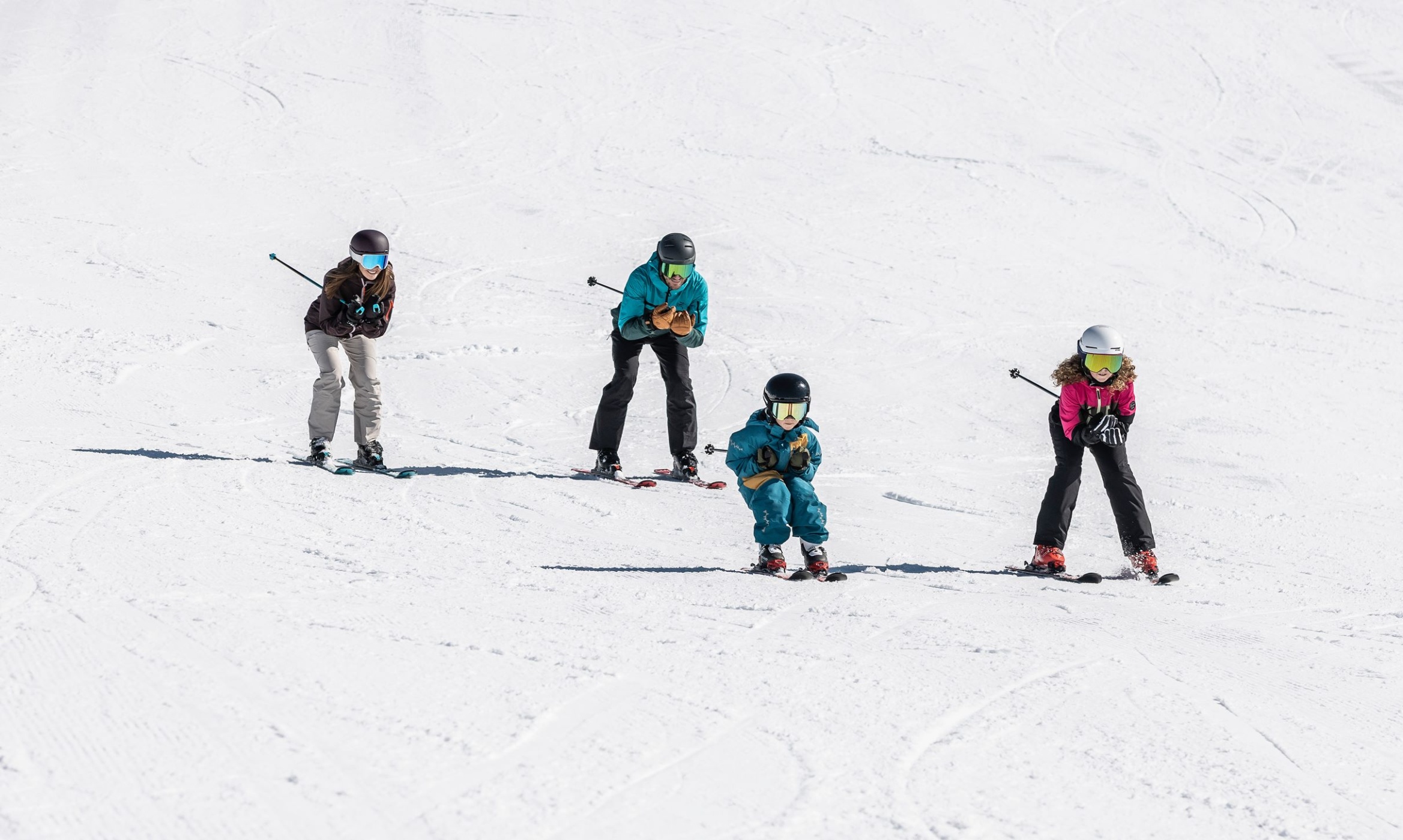 Vier Personen fahren gemeinsam Ski auf einer verschneiten Piste ©TVB_Obertauern