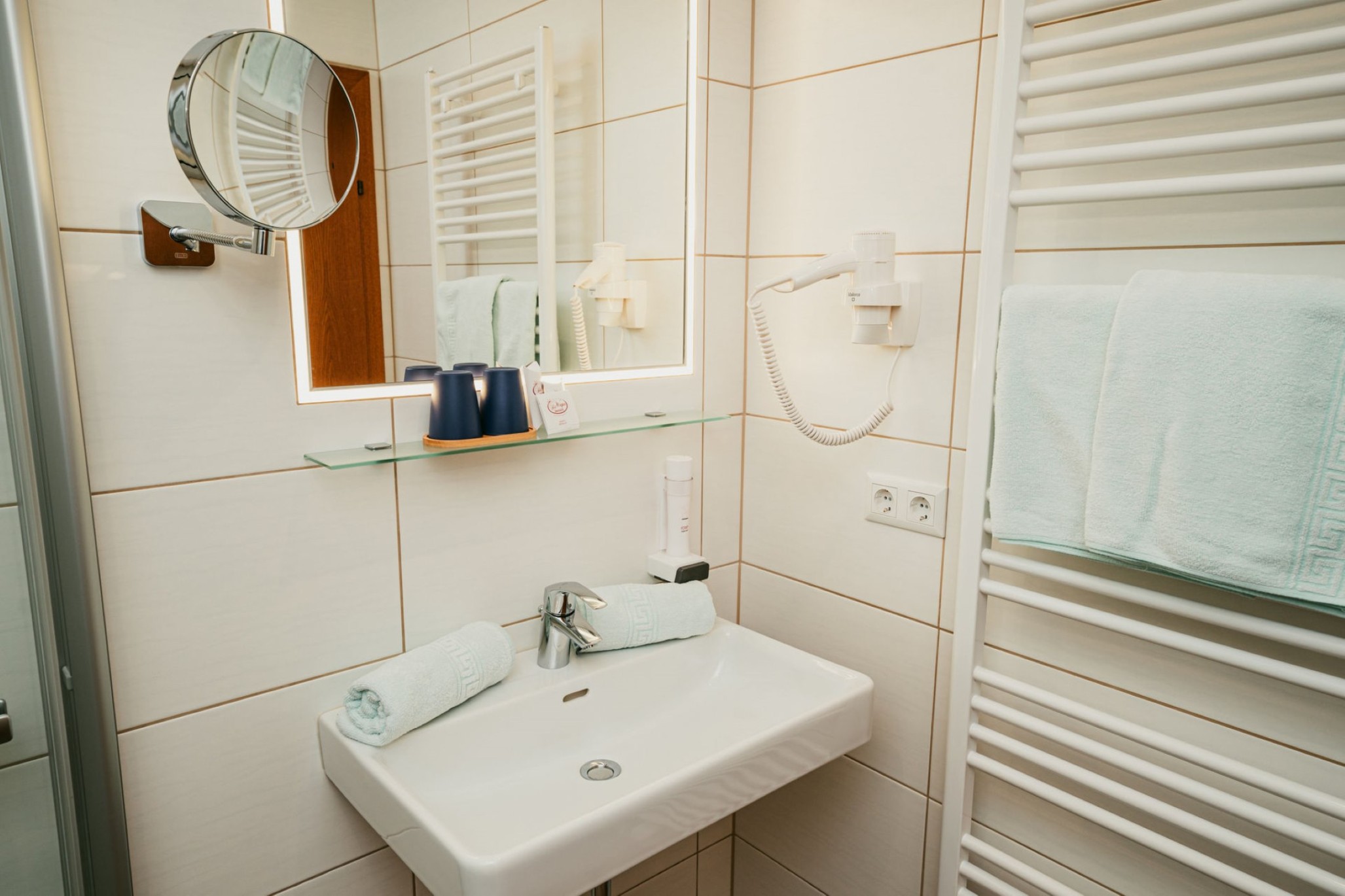 Moderner Badezimmerbereich mit Waschbecken, Spiegel und Handtüchern