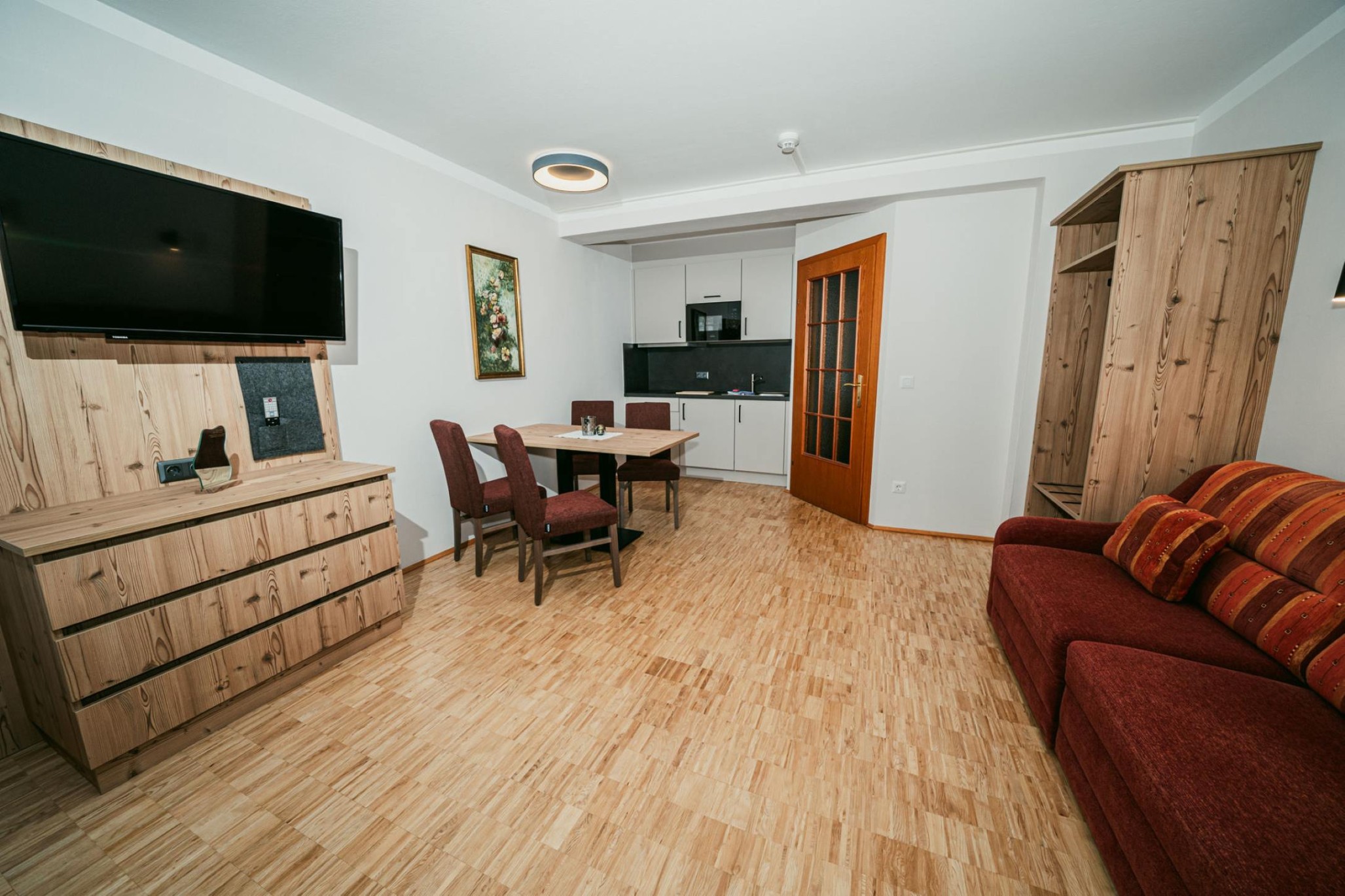 Wohnbereich mit Couch, Fernseher und Holzeinrichtung in der Ferienwohnung Typ B im Apparthotel Samson in Obertauern