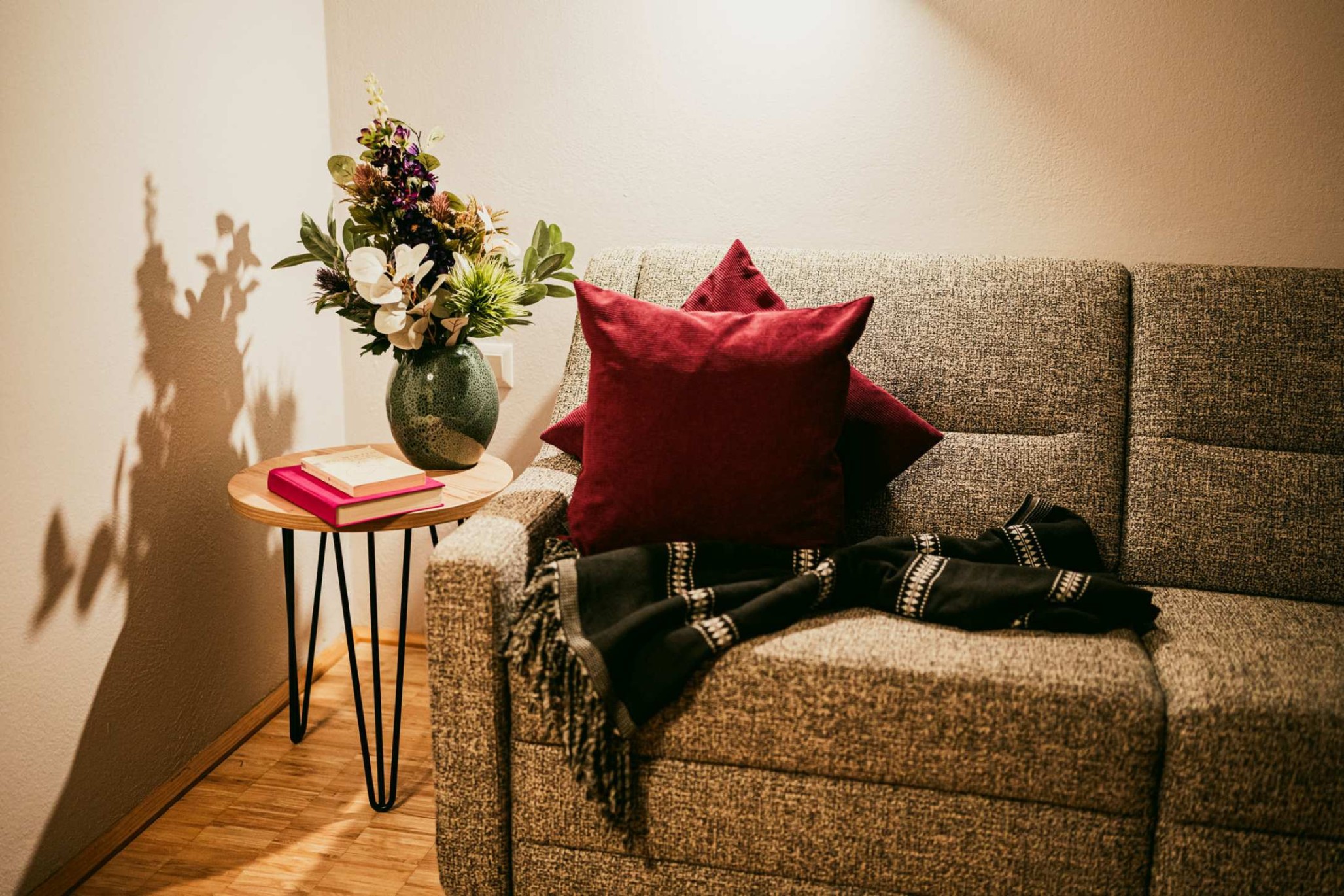 Graues Sofa mit roten Kissen und Blumen