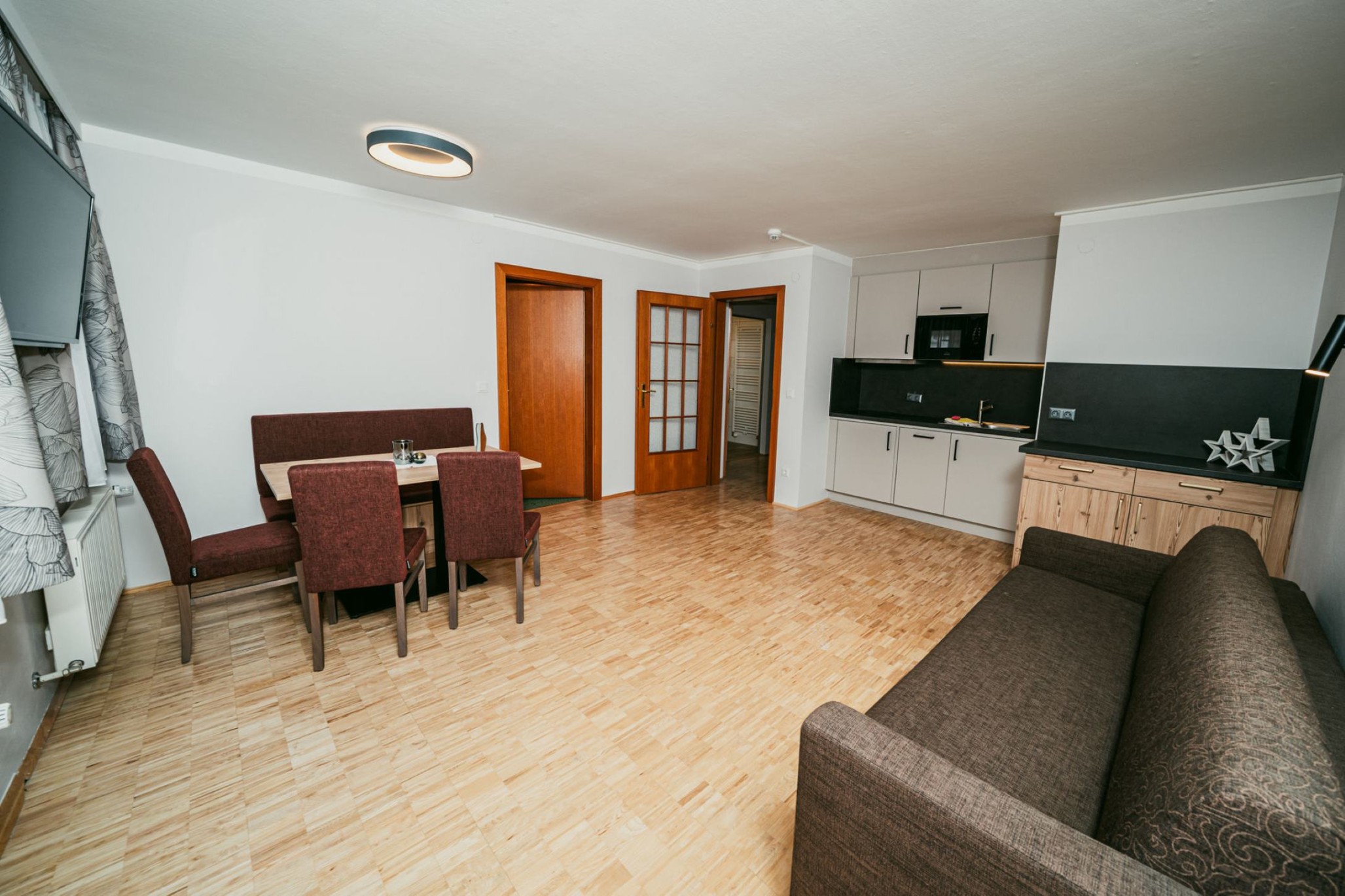 Moderner Wohnraum mit Esstisch, Stühlen, Küche und Sofa im Apparthotel Samson, Obertauern