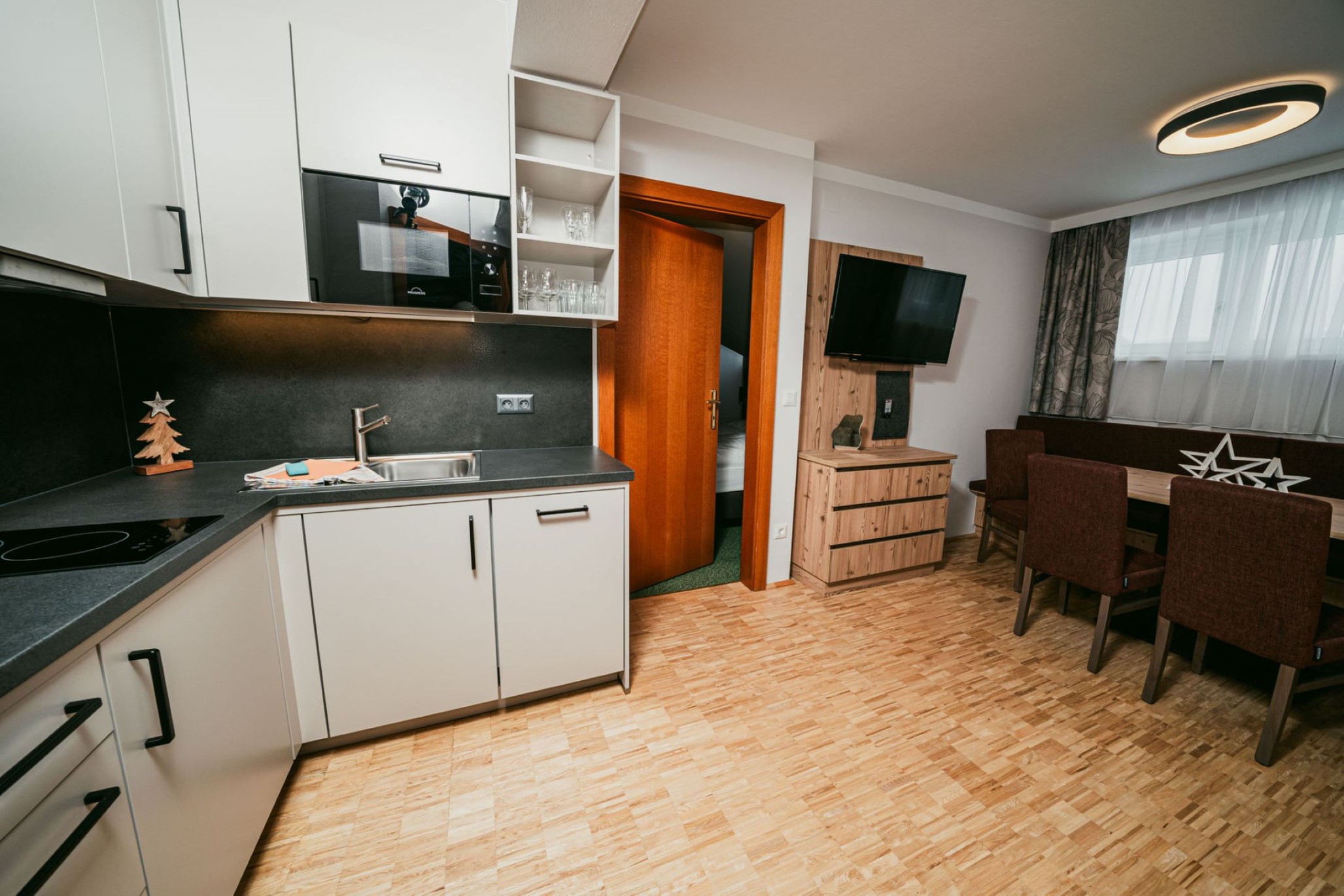 Moderne Wohnung mit Küche, Esstisch, Tür und Wandfernseher