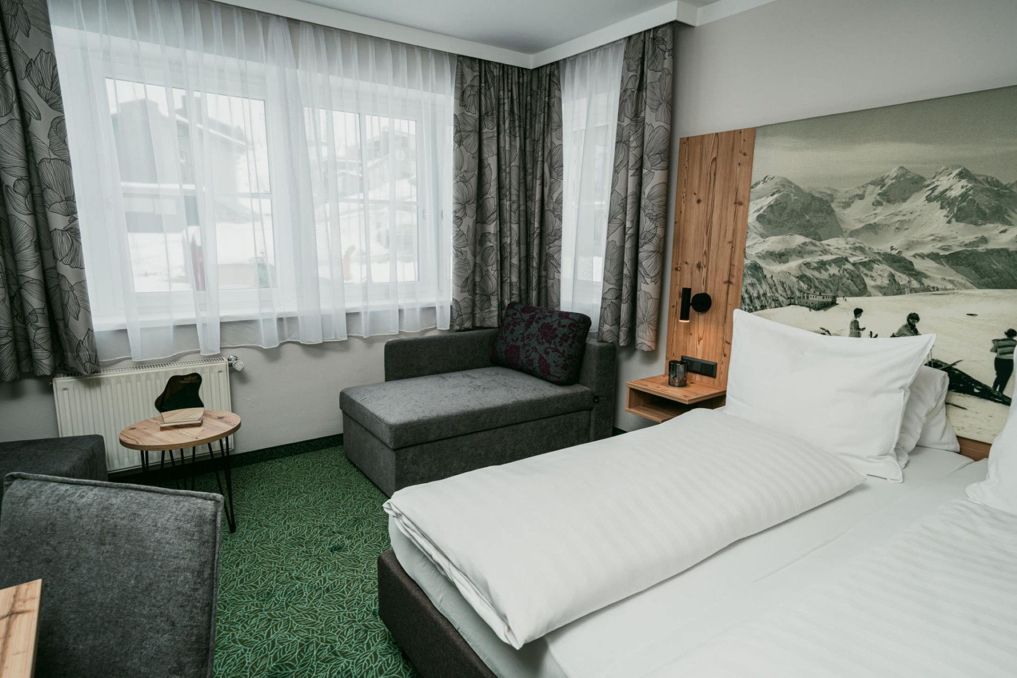 Schlafzimmer mit großen Fenstern im Komfortzimmer Standard im Apparthotel Samson in Obertauern