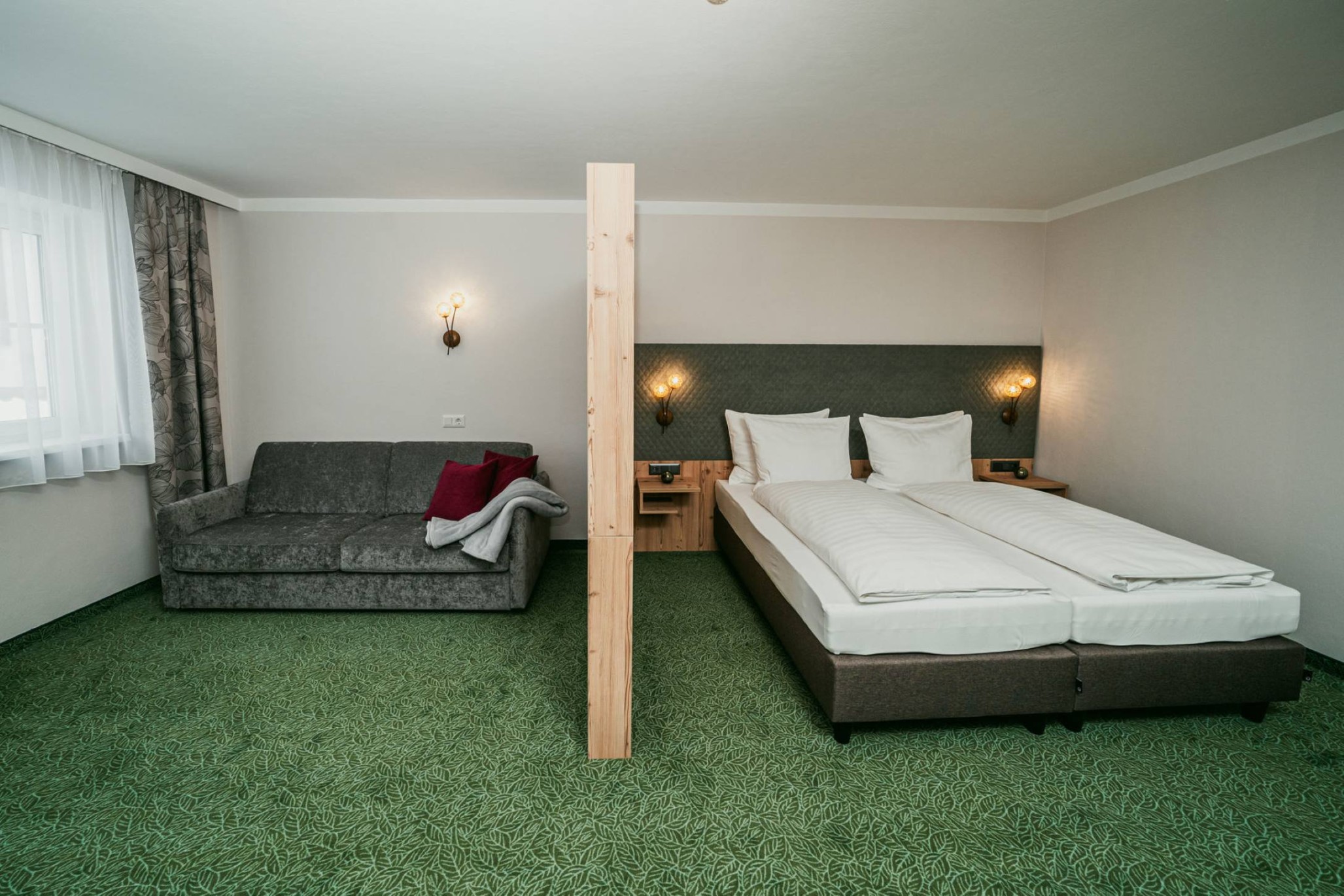 Doppelbett und Couch im Komfortzimmer Superior in Obertauern im Apparthotel Samson