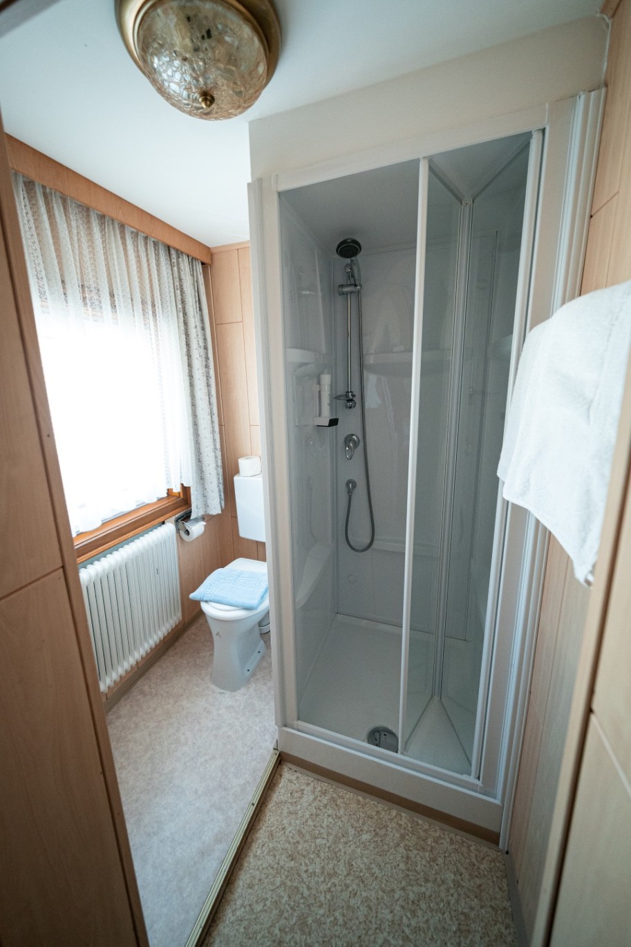 Badezimmer im Hotel Tauernpasshöhe mit Dusche, hellen Fliesen und Fenster für natürliches Licht.