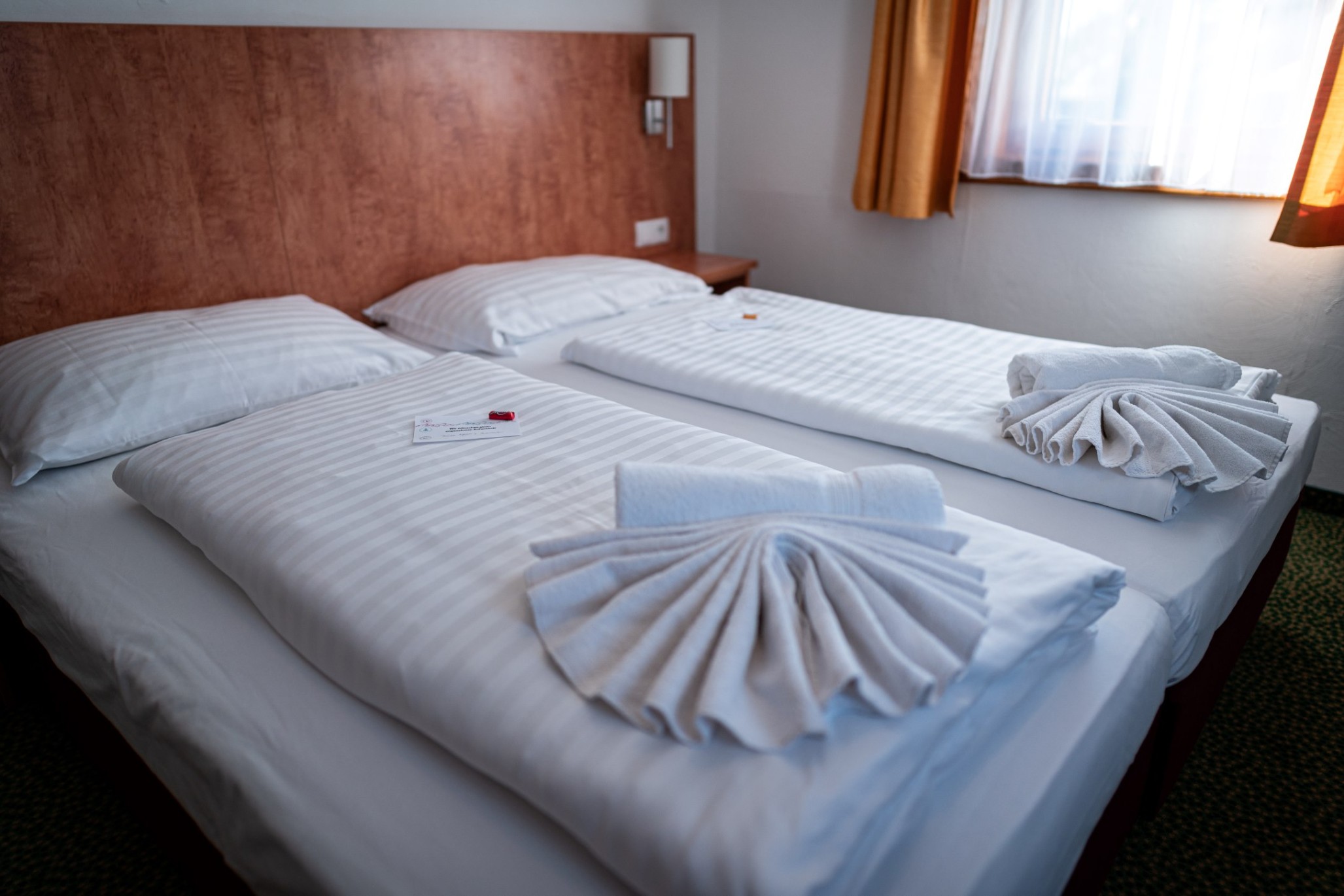 Gemütliches Doppelzimmer im Hotel Tauernpasshöhe mit hellen Holzflächen und kunstvoll gefalteten Handtüchern.