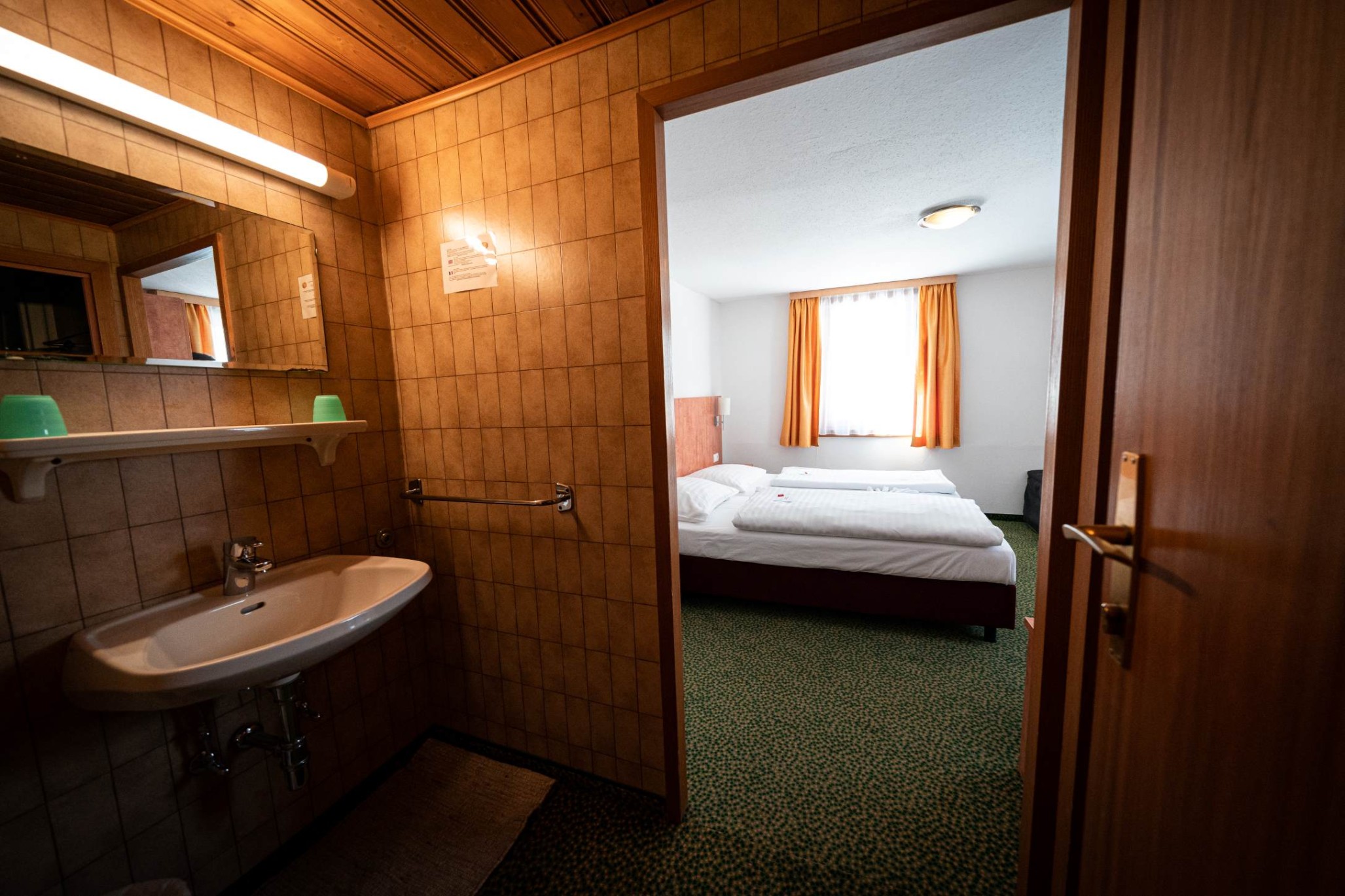 Zimmer im Hotel Tauernpasshöhe mit Zugang zum Badezimmer und Fensterblick auf die Umgebung