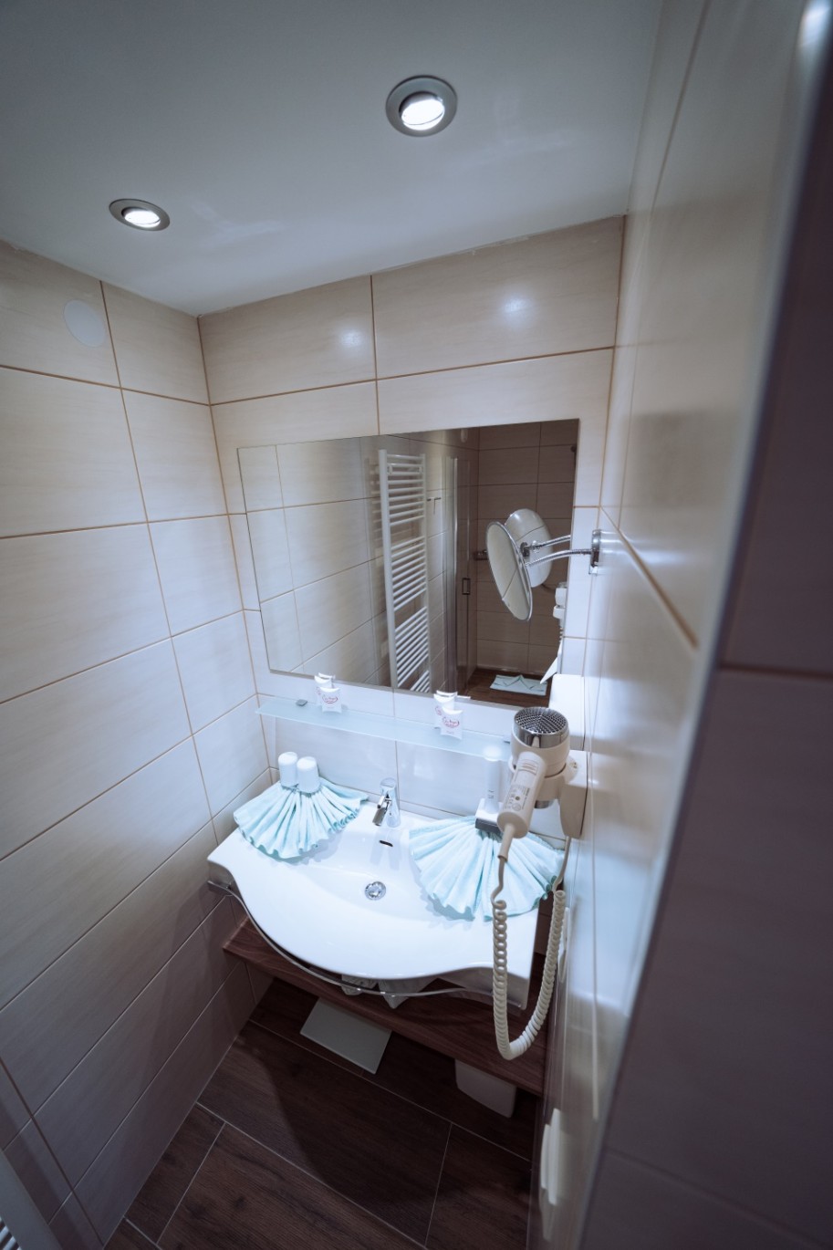 Modernes Badezimmer mit Waschbecken, Spiegel, Haartrockner und Handtuchdekorationen